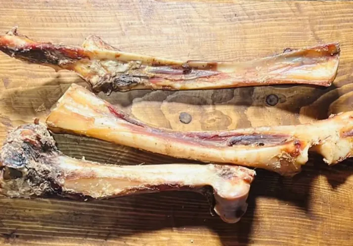 Three raw venison leg bones on a wooden table